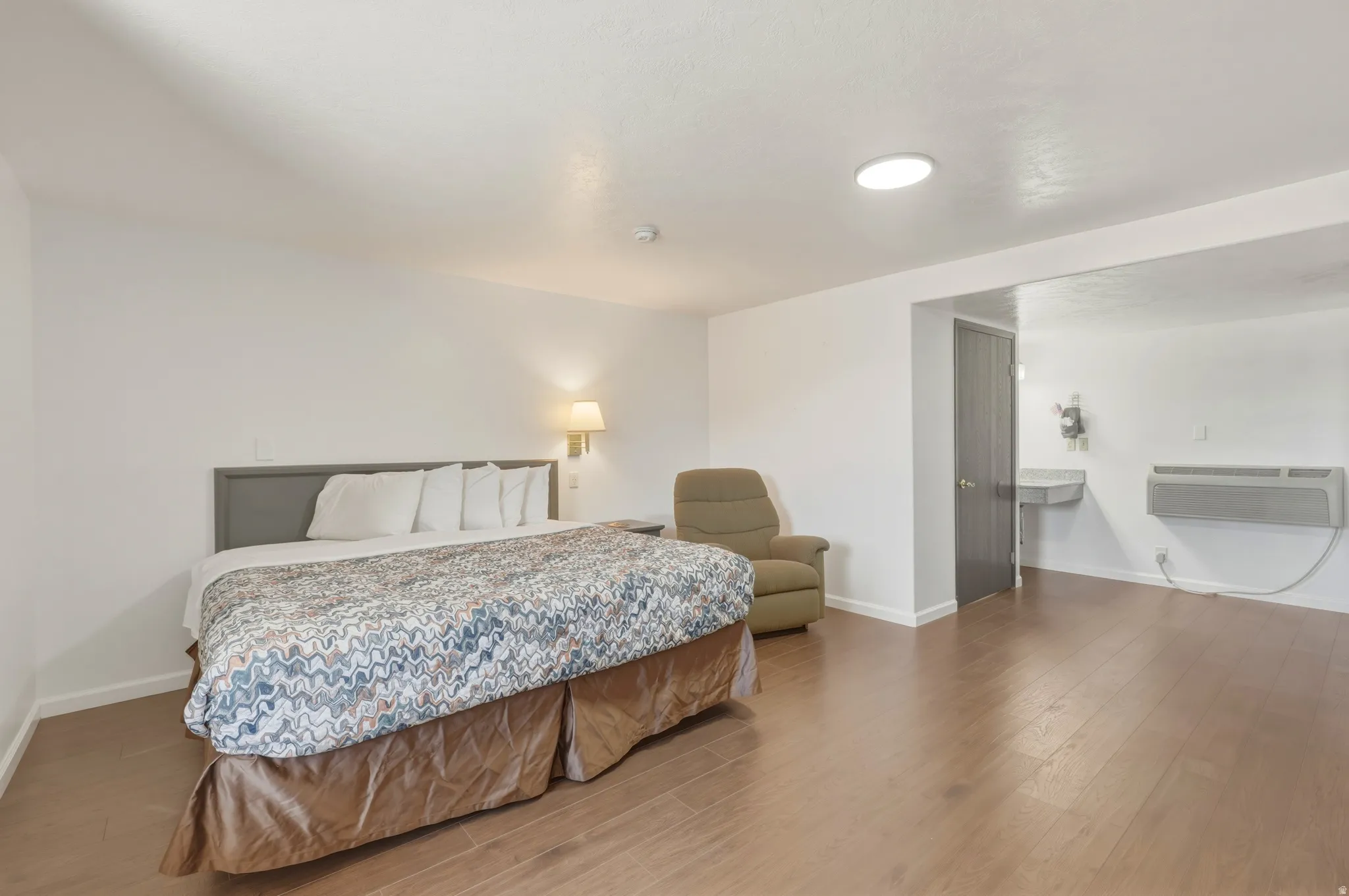 Spacious room featuring wood-finish flooring, white walls, and recessed lighting