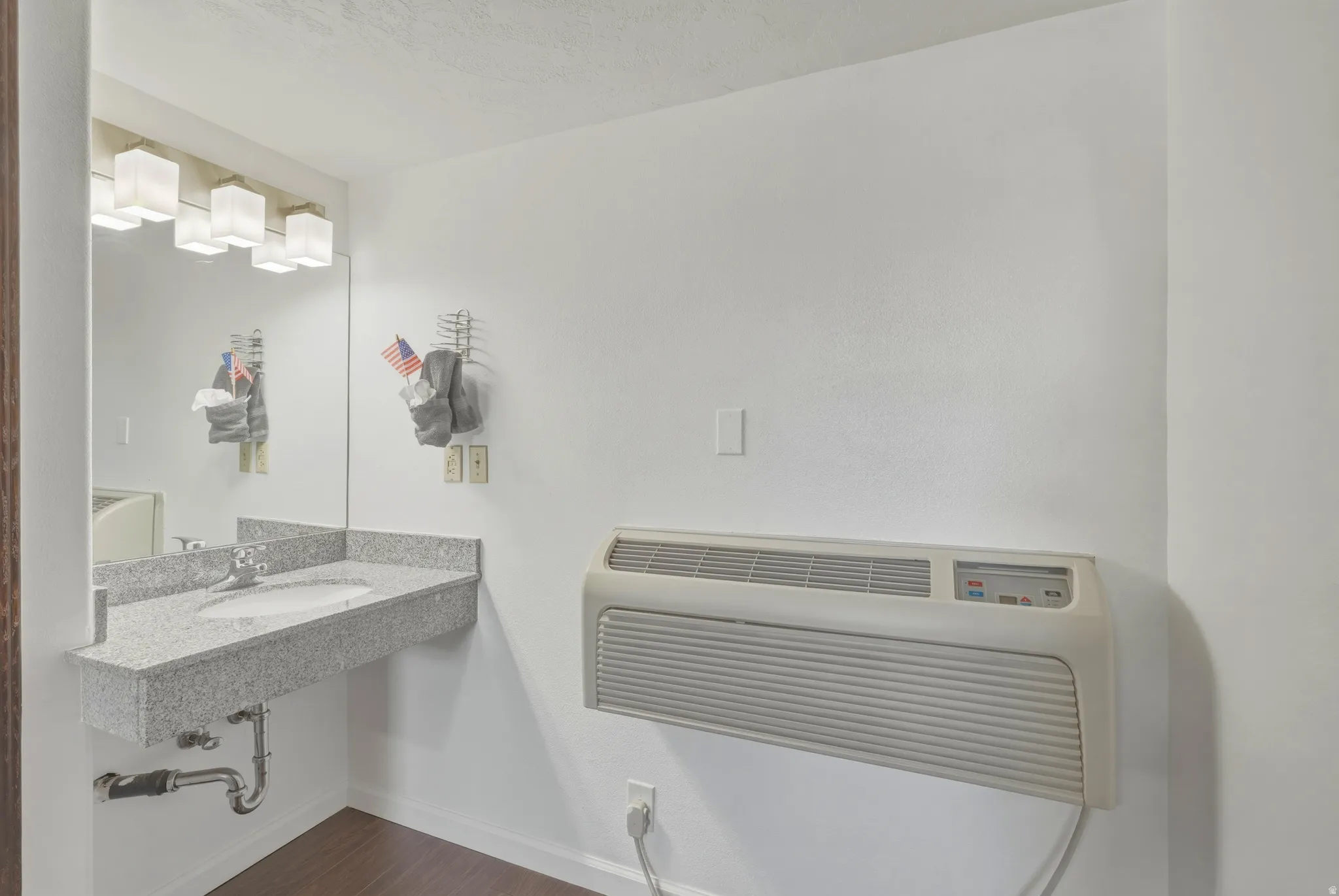 Floating vanity with a light-toned stone-finish countertop, undermount sink, and chrome faucet