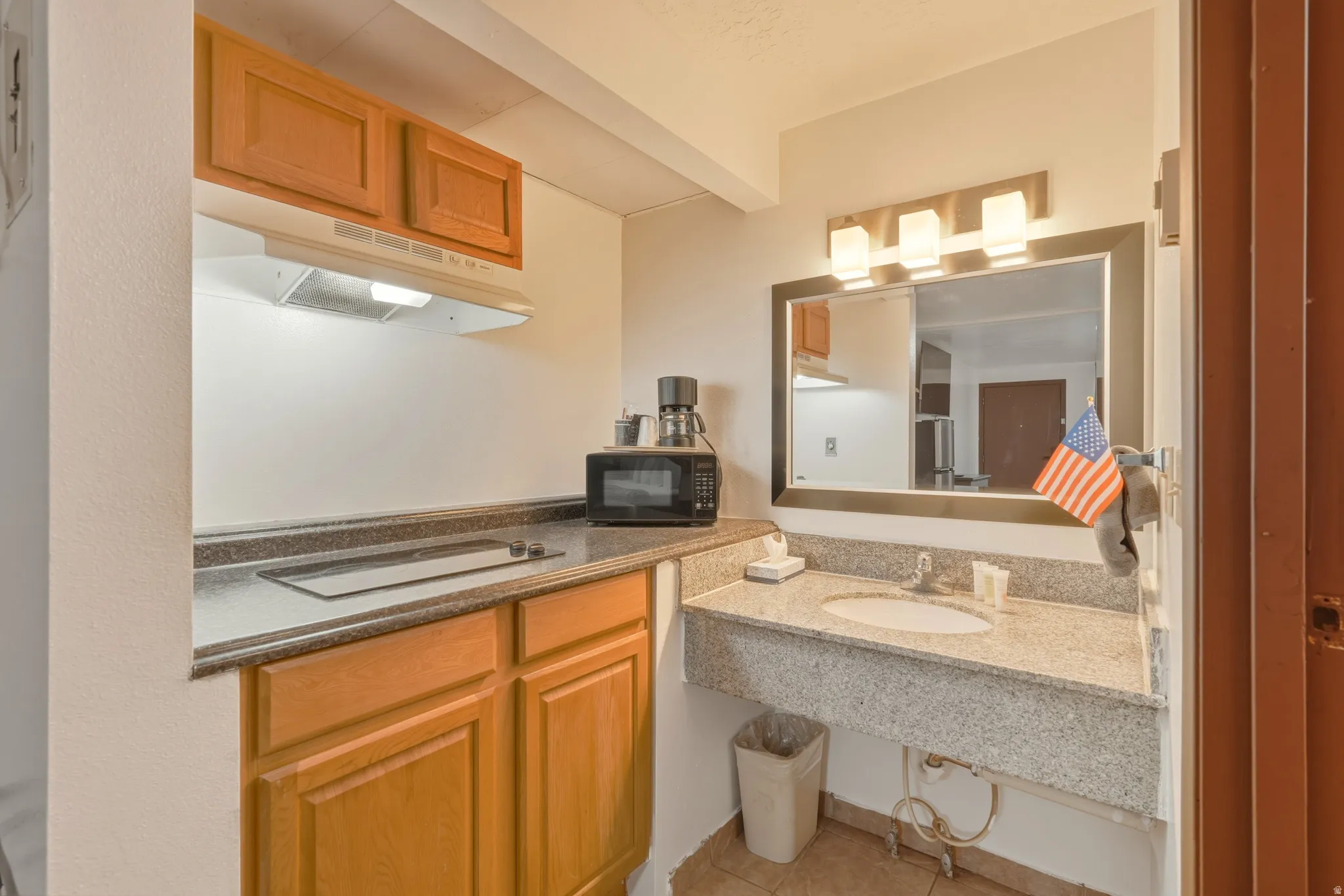 Compact kitchen area featuring wood cabinetry, stone-finish countertops, and an integrated cooktop