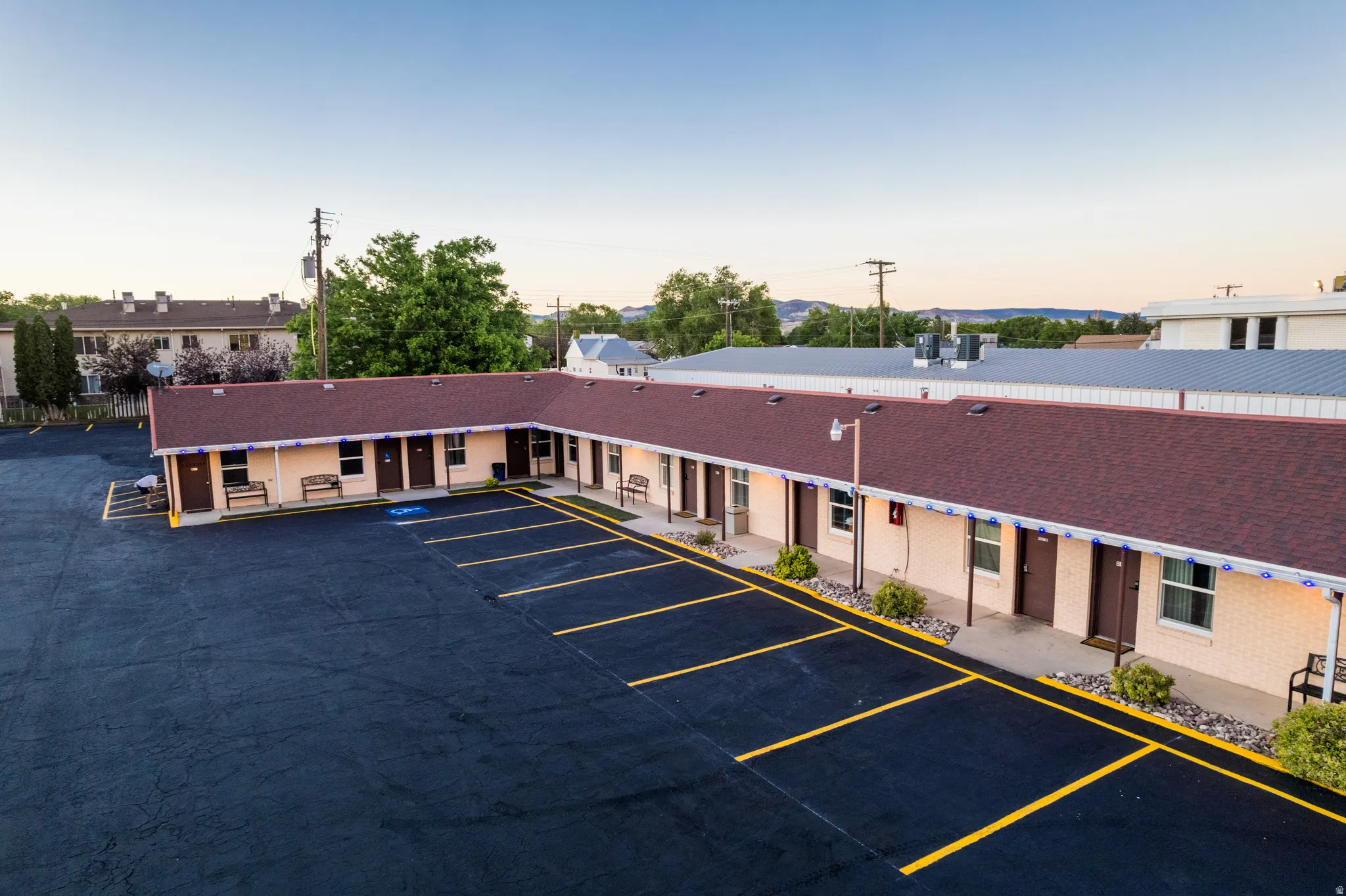 L-shaped commercial building with a dark shingle roof and light-colored brick exterior
