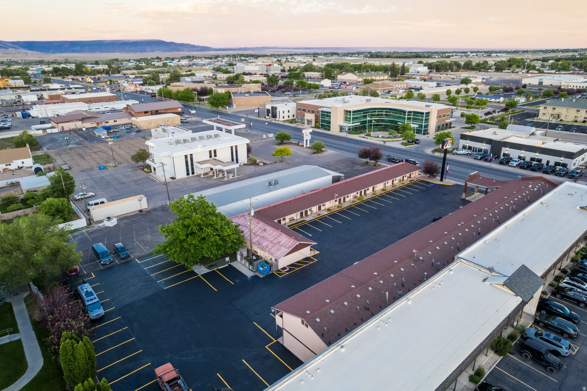 Expansive commercial property featuring multiple structures, a large paved parking area with marked spaces, and established trees