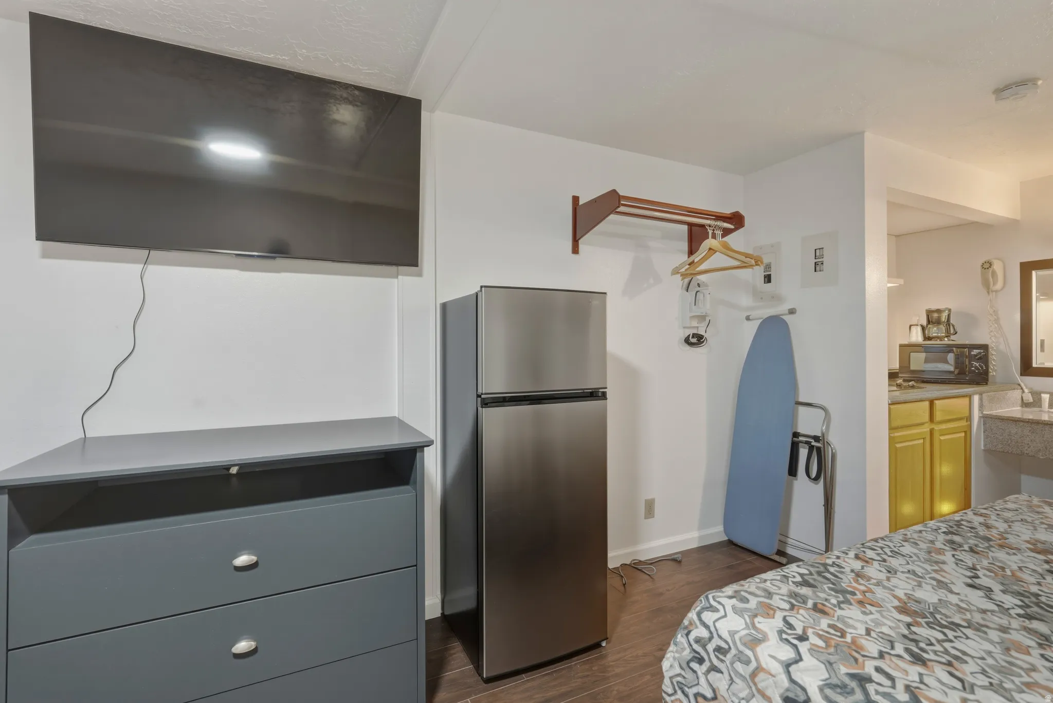 Wall-mounted television with corner console, stainless steel refrigerator, and wood-finish flooring