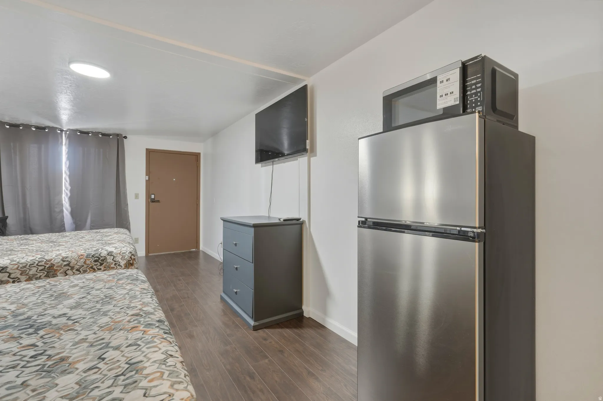 Compact kitchen area featuring a stainless steel refrigerator with an upper freezer and a countertop microwave
