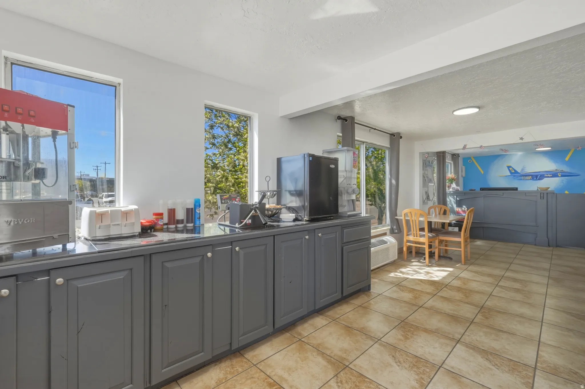 Commercial space featuring extensive dark-finish cabinetry with light-toned hardware, durable tile flooring, and multiple windows providing natural light