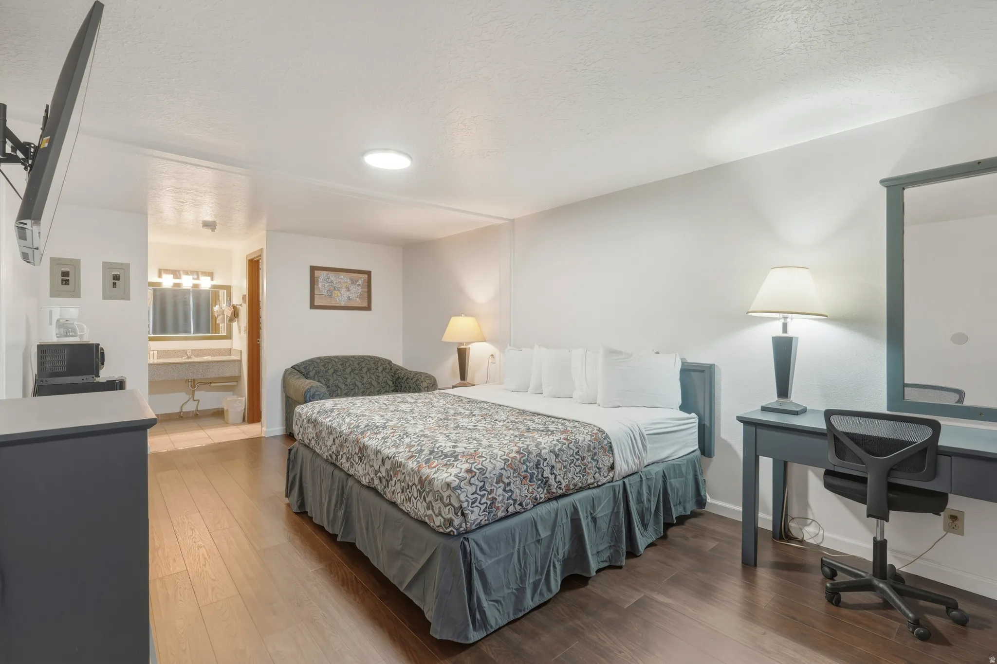 Bedroom featuring wood-finish flooring, a wall-mounted television, and an integrated desk area