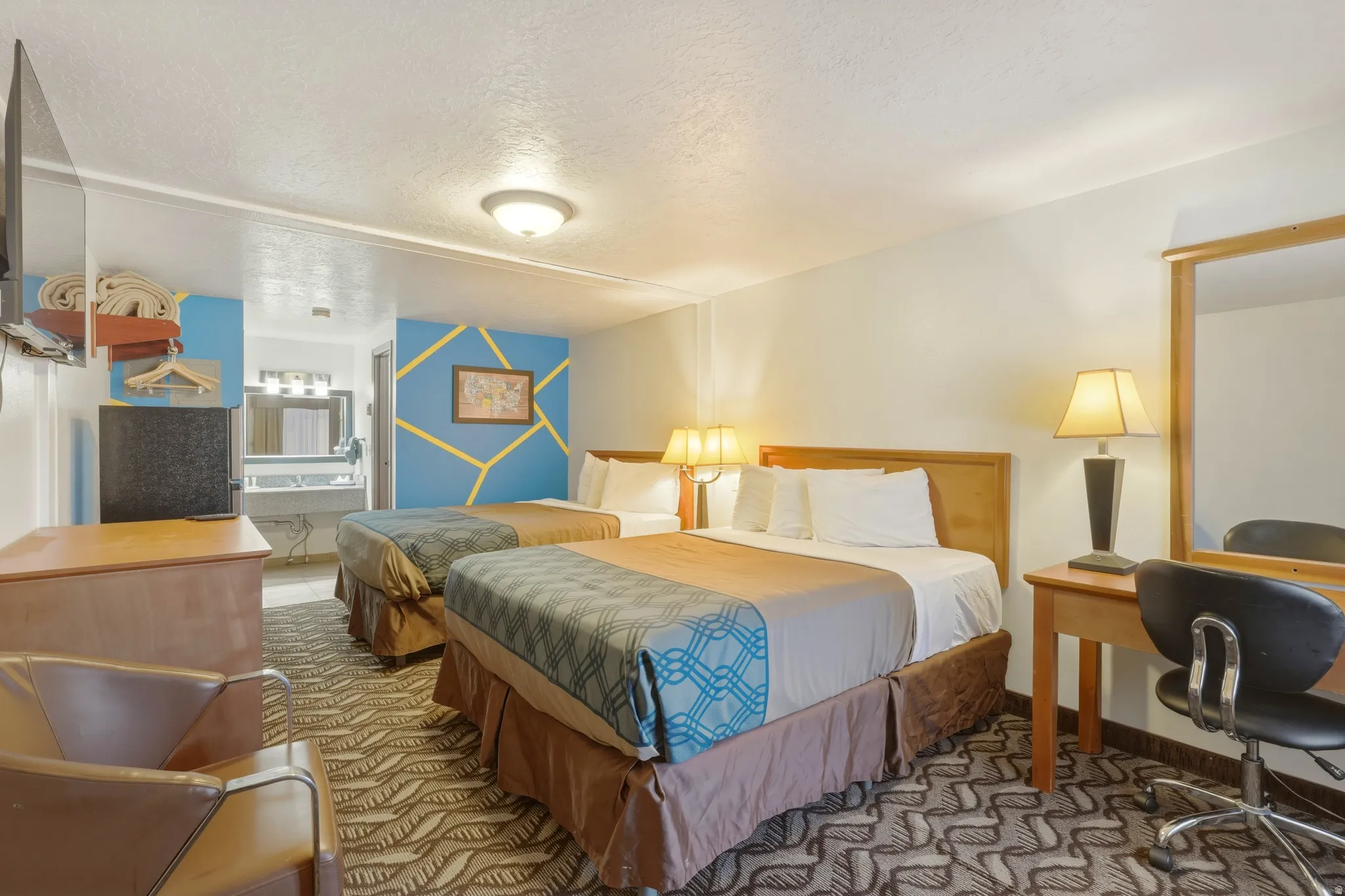 Bedroom featuring two beds, a built-in dressing table with mirror, and a television