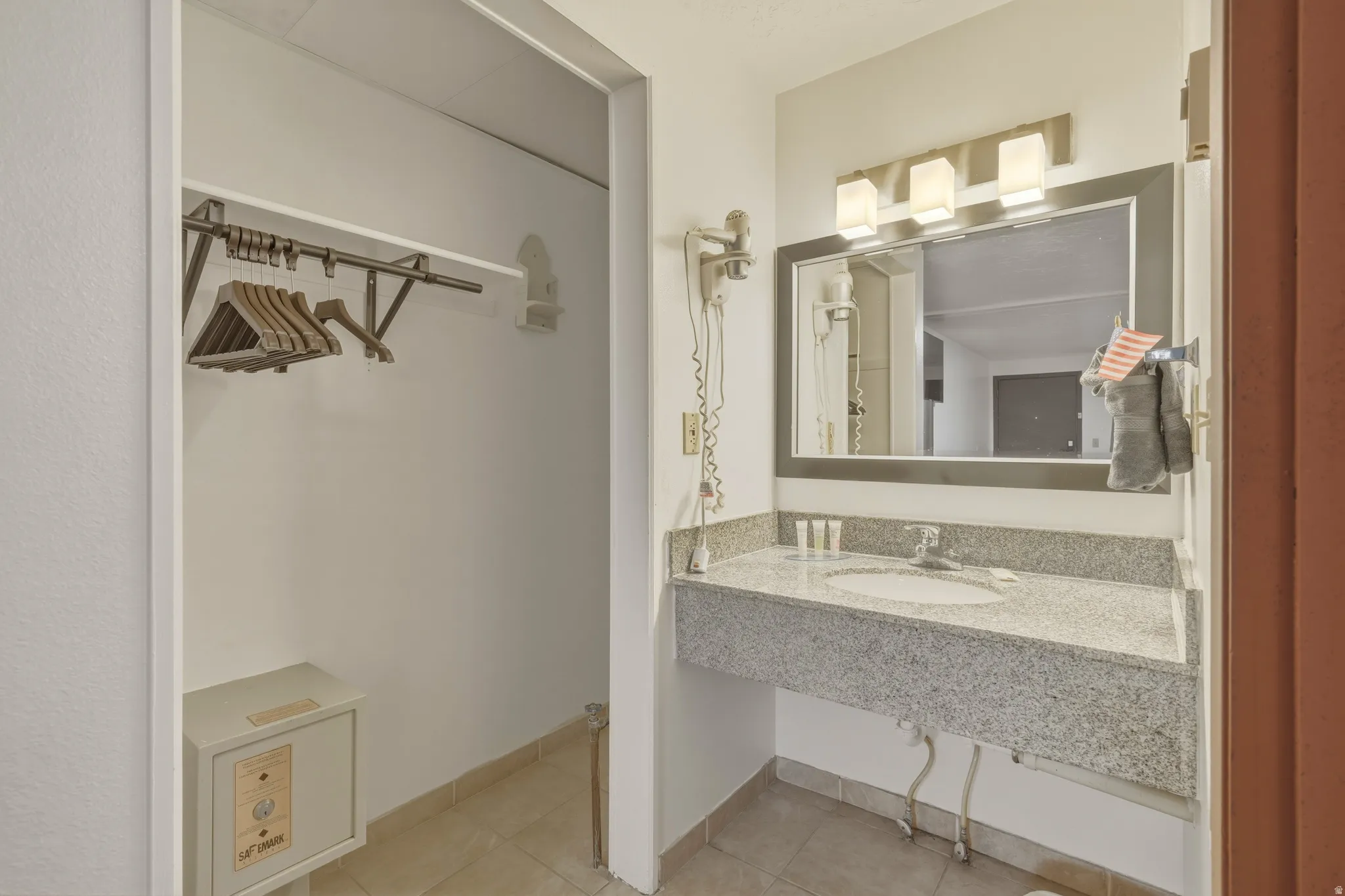 Vanity area featuring a granite-style countertop, integrated sink, and an overhead three-light fixture