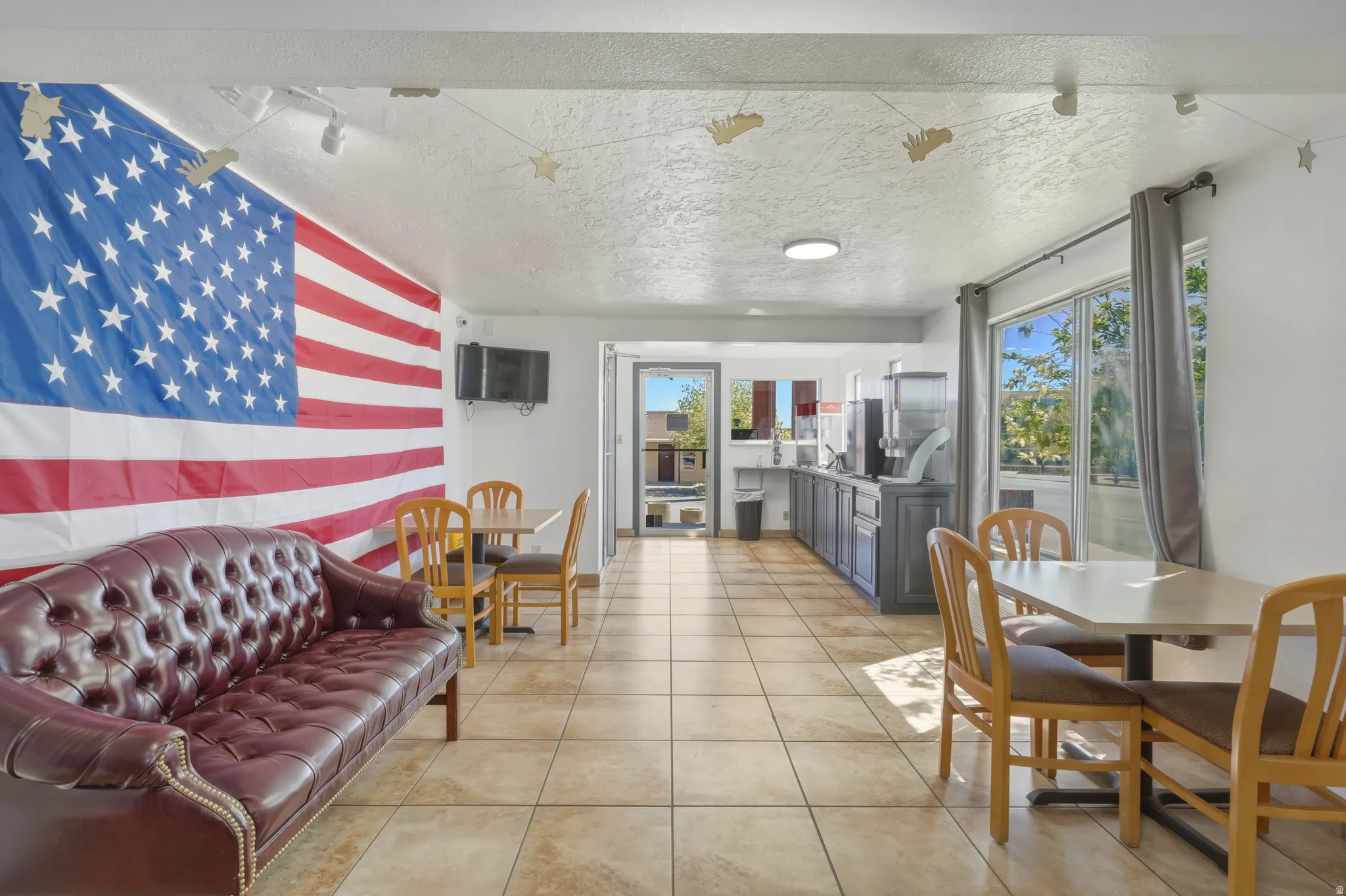 Spacious interior area featuring neutral-toned tile flooring, recessed lighting, and a window with vertical blinds