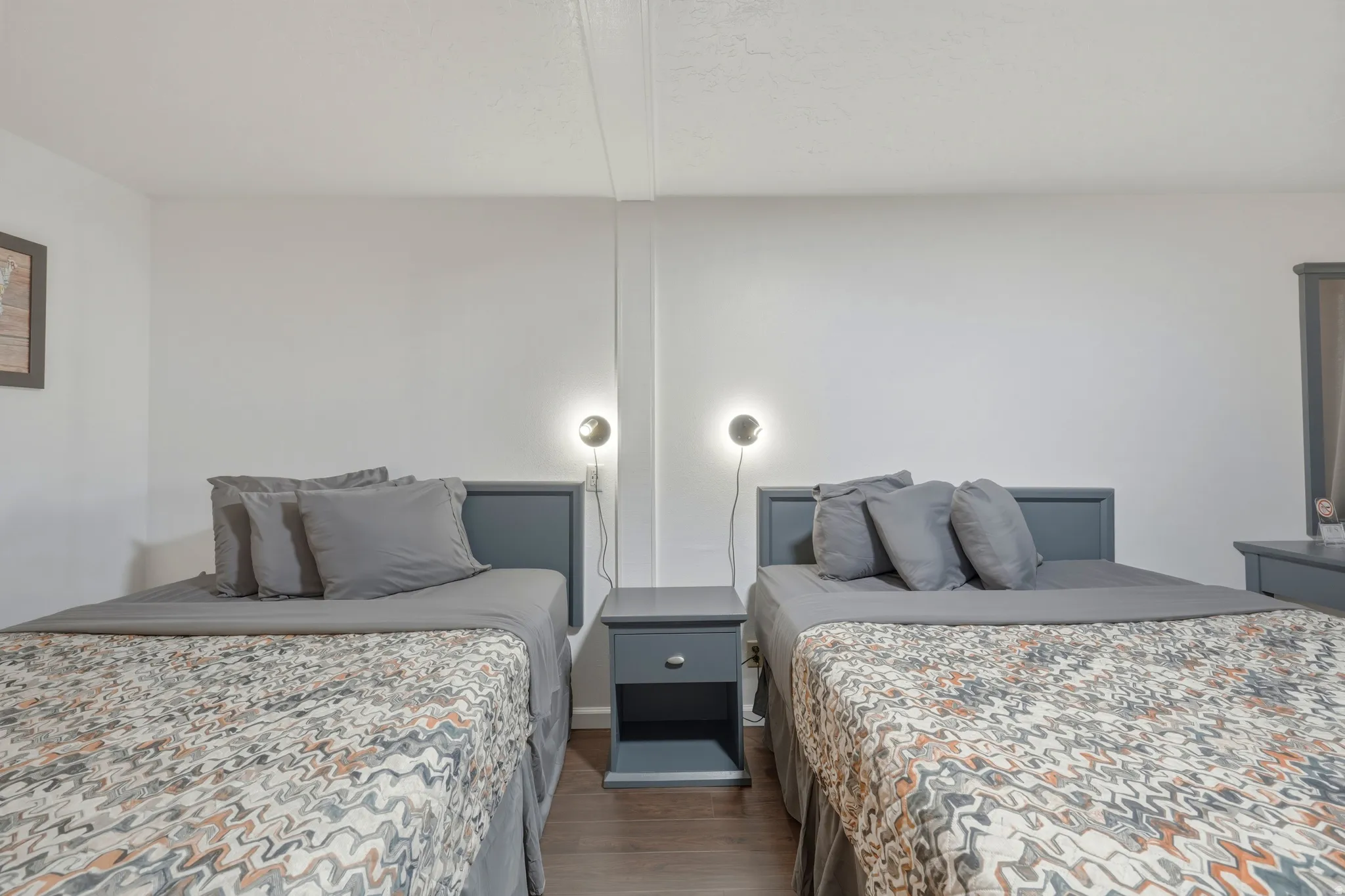 Bedroom featuring two beds with dark wood headboards, two coordinating nightstands, and two wall-mounted sconces