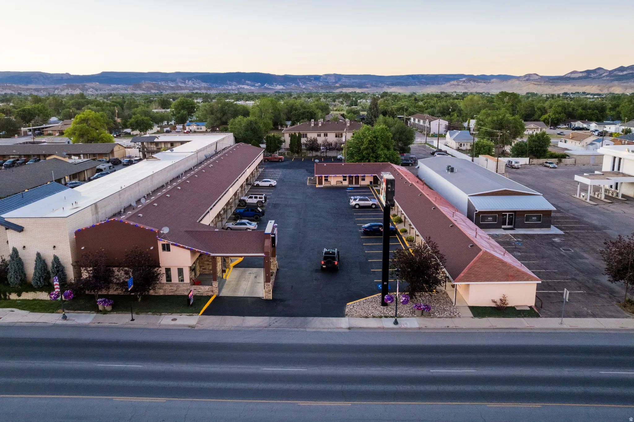Expansive commercial property featuring multiple structures, paved parking areas, and mature landscaping