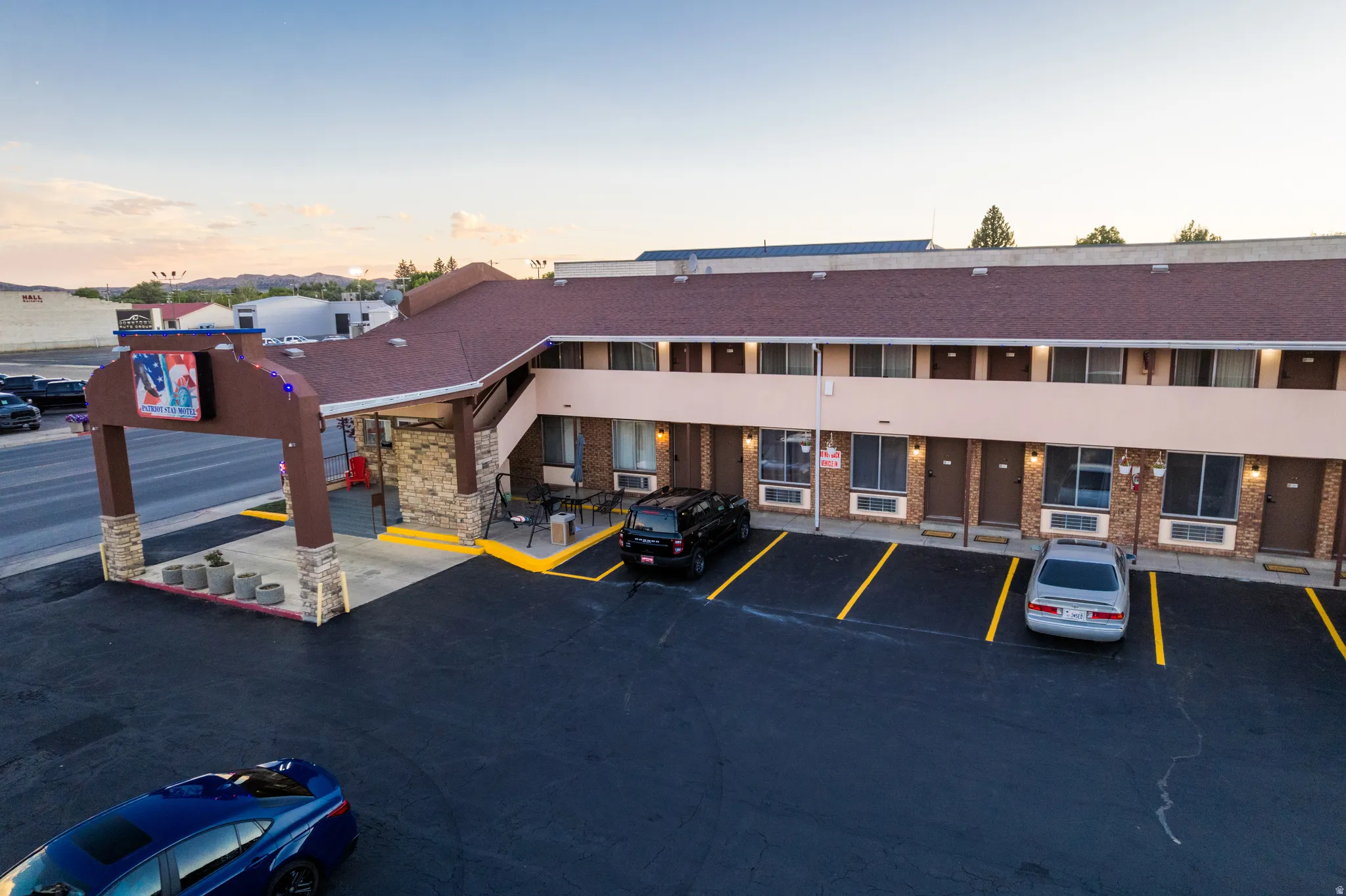 Two-story commercial building featuring a dark shingle roof and a beige stucco facade with brick accents