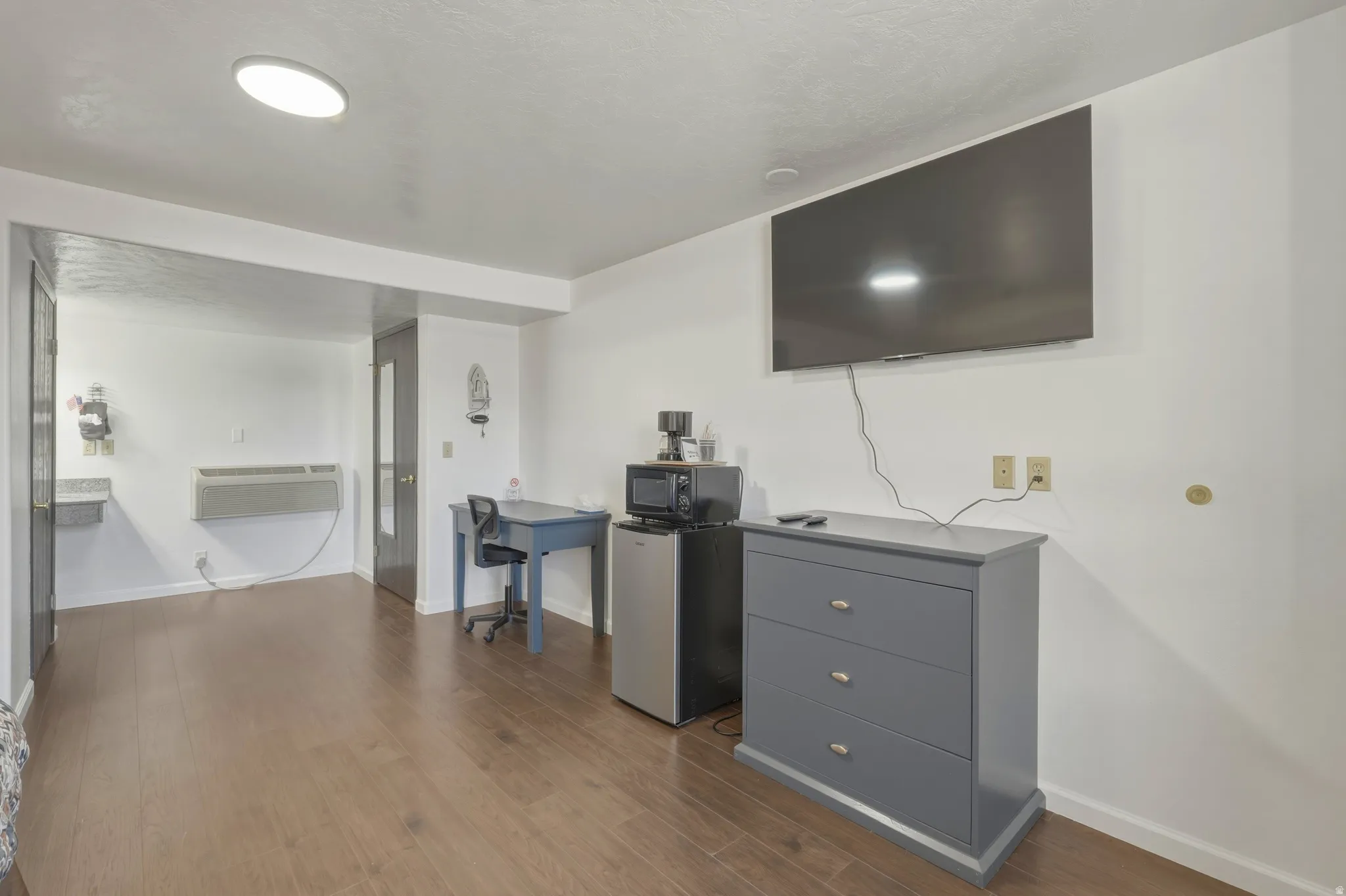 Open living area featuring wood-finish flooring, white walls, and an overhead flush-mount light fixture