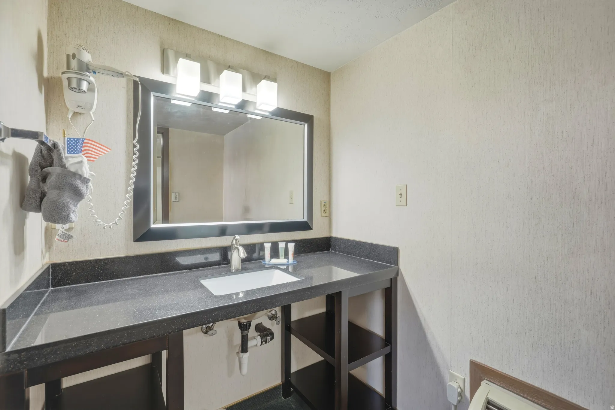 Vanity featuring a dark countertop, white rectangular undermount sink, and polished chrome faucet