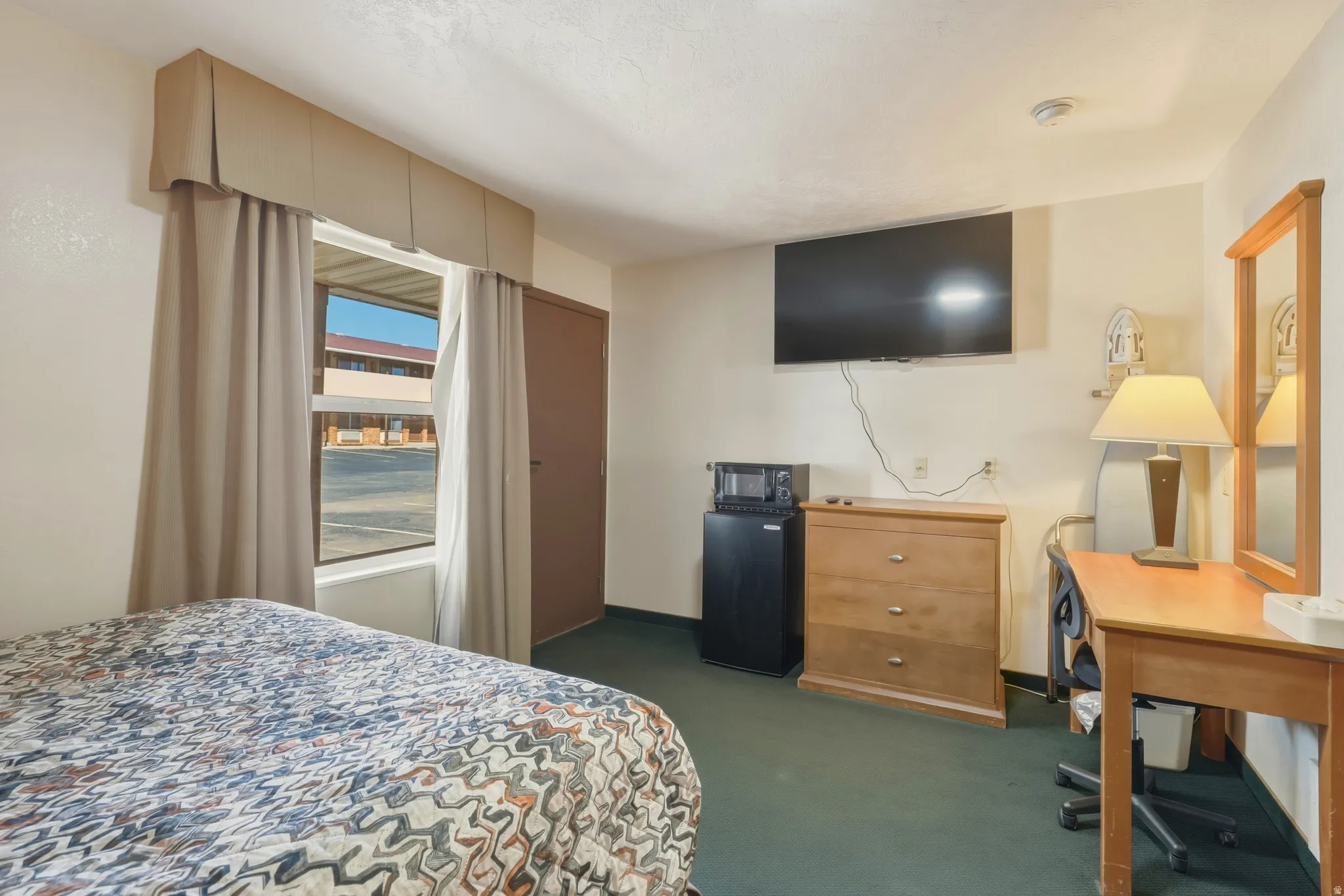 Room featuring wall-mounted television, built-in window valance, and wall-to-wall carpeting
