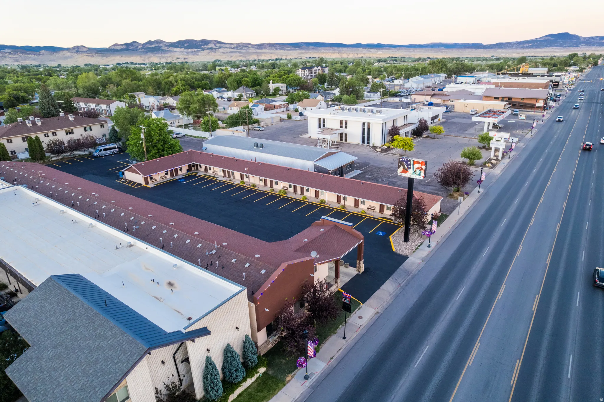Expansive commercial property featuring a large asphalt parking lot, multiple adjacent buildings, direct street frontage, and a prominent commercial sign