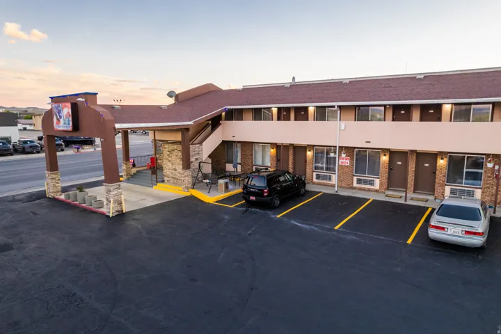 Multi-story building featuring a brown shingle roof, stone veneer accents, and stucco siding