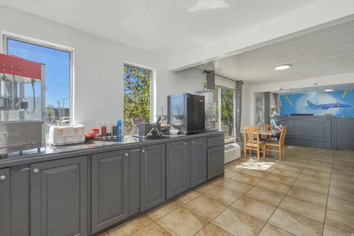 Commercial space featuring extensive dark-finish cabinetry with light-toned hardware, durable tile flooring, and multiple windows providing natural light