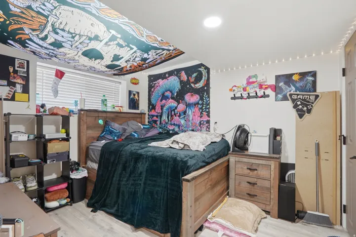 Bedroom featuring light-tone wood-finish flooring and a white ceiling with recessed lighting