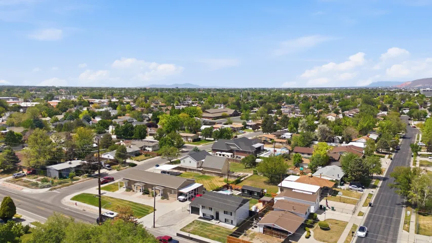 Expansive residential area featuring numerous single-family homes, mature trees, paved streets, and mountain ranges in the distance