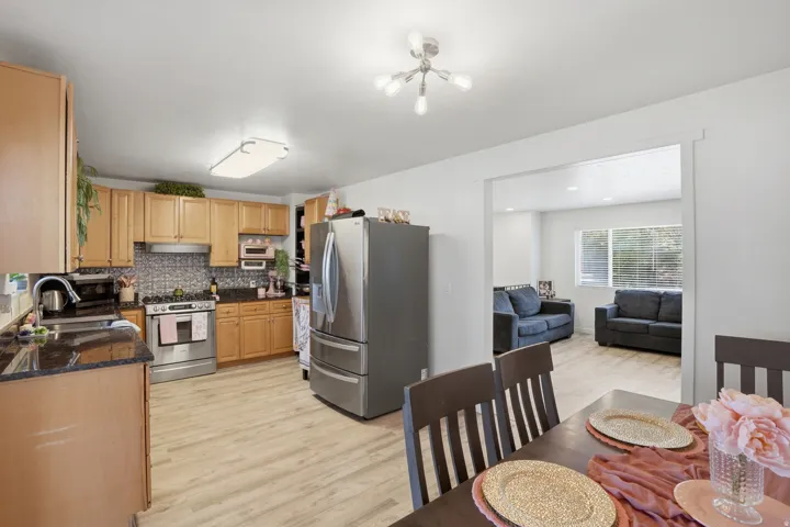 Kitchen featuring wood-finish cabinetry, dark countertops, a mosaic tile backsplash, and stainless steel appliances