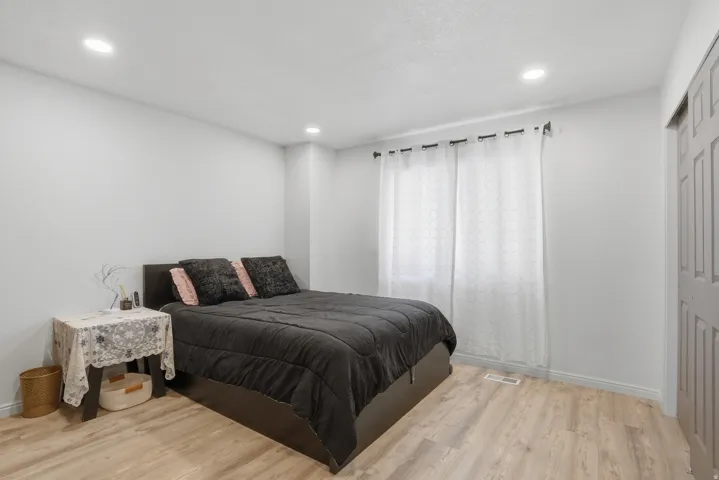 Bedroom with light wood-finish flooring, white walls, and recessed lighting