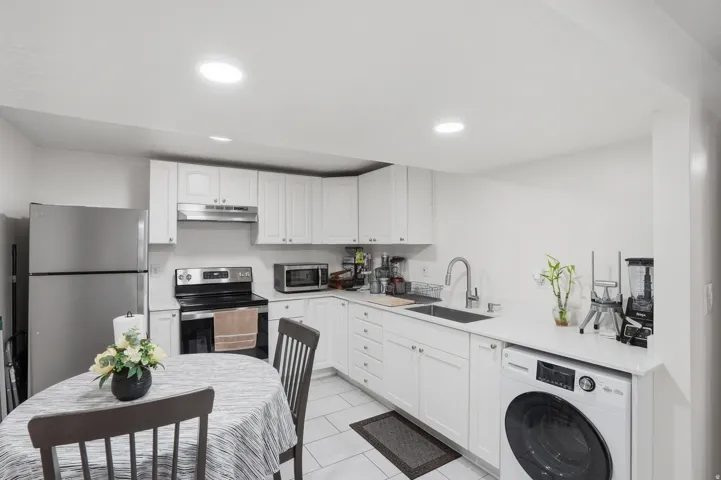 Kitchen featuring white cabinetry, stainless steel appliances, a tile backsplash, light-colored countertops, and recessed lighting