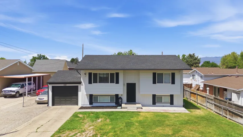 Split-level residence featuring white siding, a dark asphalt shingle roof, and a single-car garage