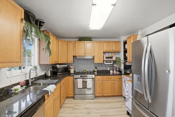 Kitchen with natural wood-finish cabinetry, dark speckled countertops, and a subway tile backsplash
