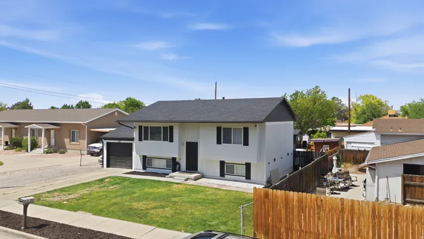 Two-story residence featuring white siding, black window shutters, a dark roof, and a single-car garage
