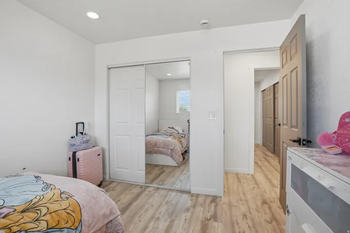 Interior room featuring light wood-finish flooring, white walls, and a sliding mirrored closet door