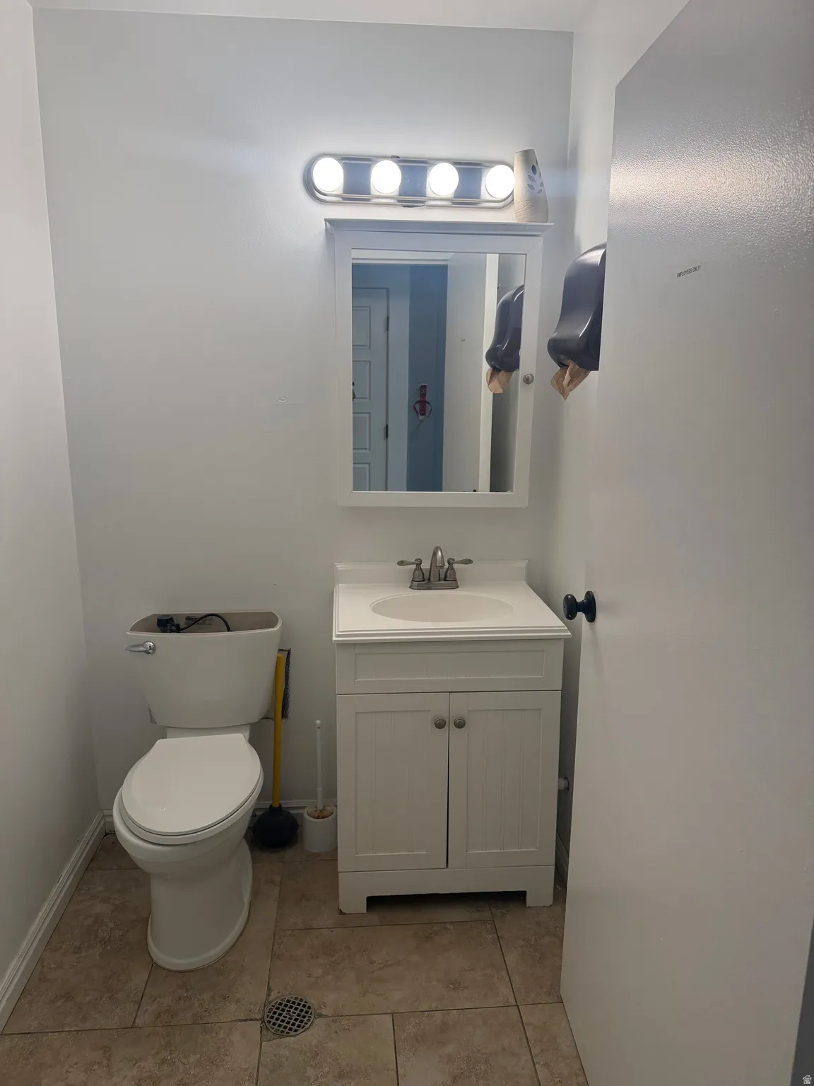 Compact bathroom featuring a white vanity with a built-in sink, brushed nickel faucet, and a wall-mounted medicine cabinet