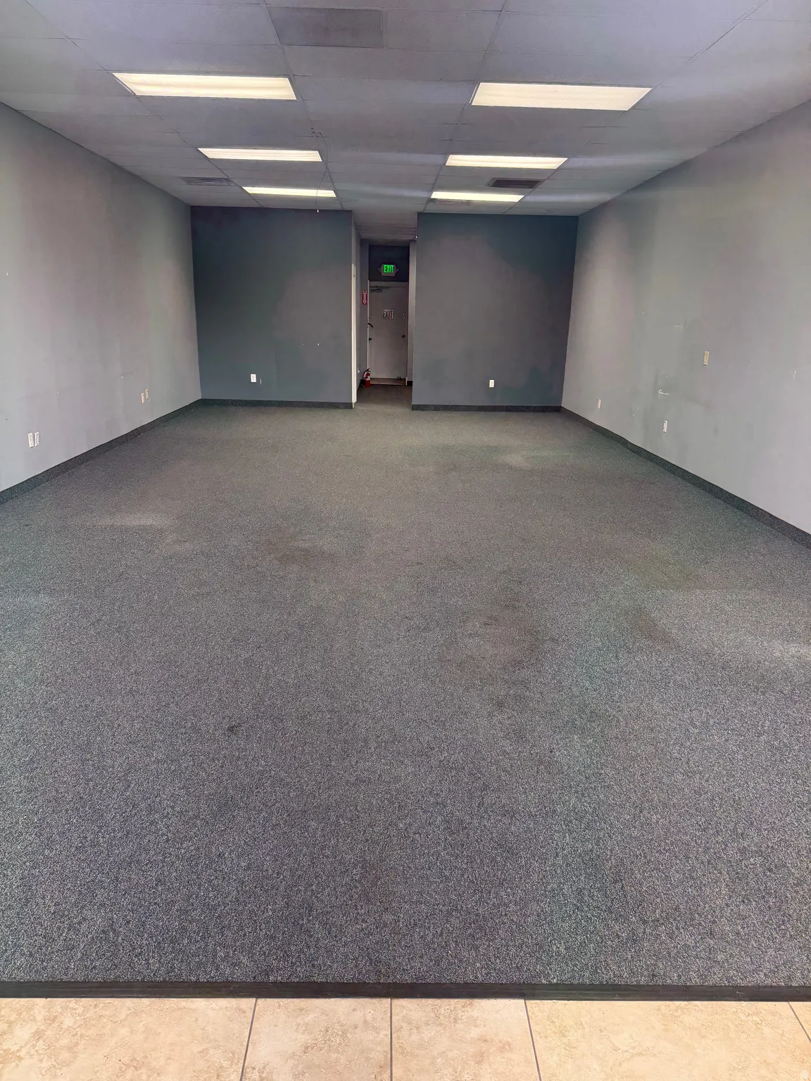 Spacious commercial interior featuring dark gray carpeting and light gray walls