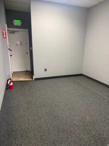 Carpeted interior space with a dropped ceiling and light-toned walls