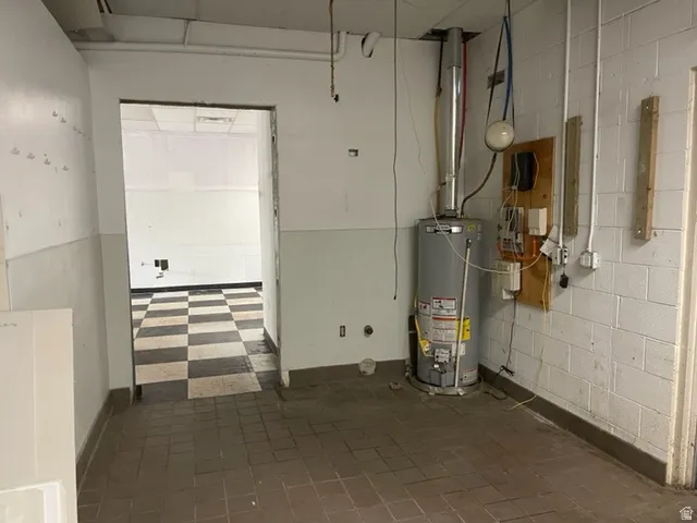 Utility area featuring a water heater, exposed piping, and electrical components