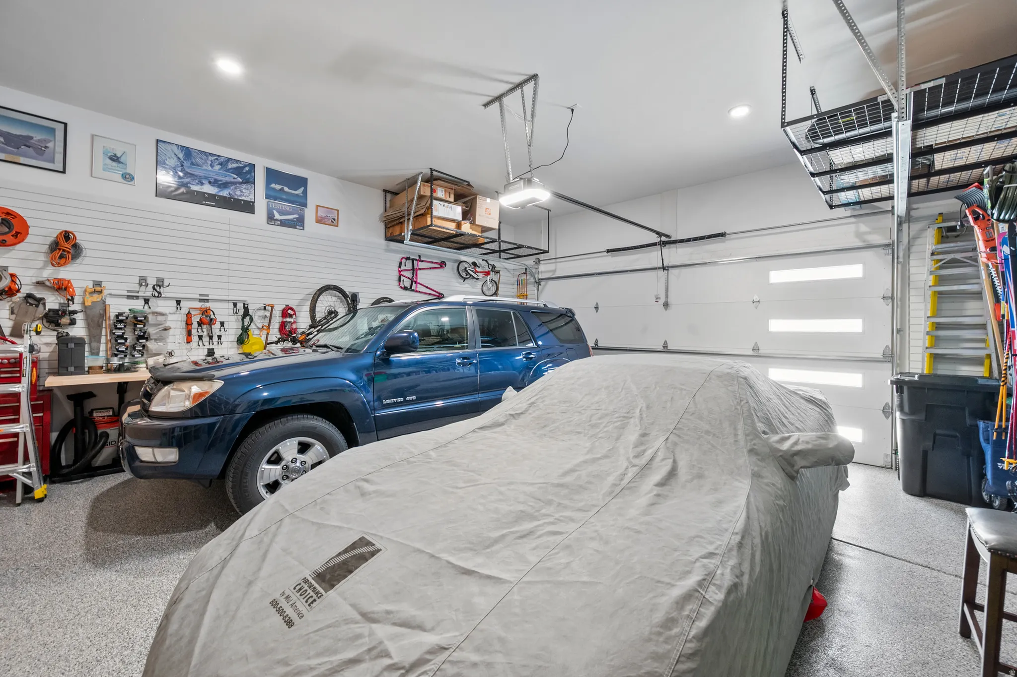 Spacious garage featuring an epoxy-coated floor, slatwall storage system, recessed lighting, and two sectional garage doors with frosted window inserts