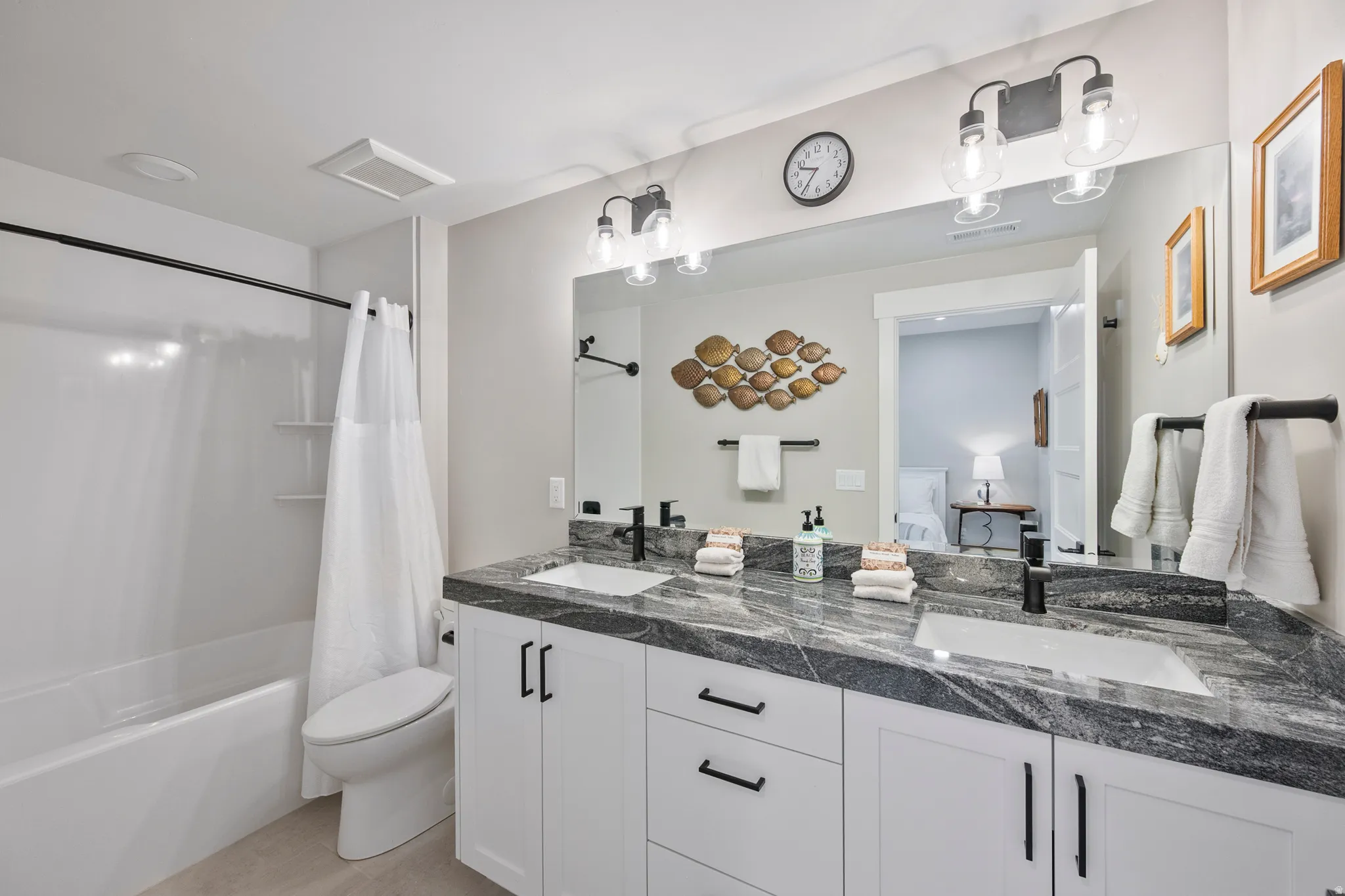 Ensuite Bathroom featuring a dual vanity with a patterned countertop, individual undermount sinks, and matte black hardware