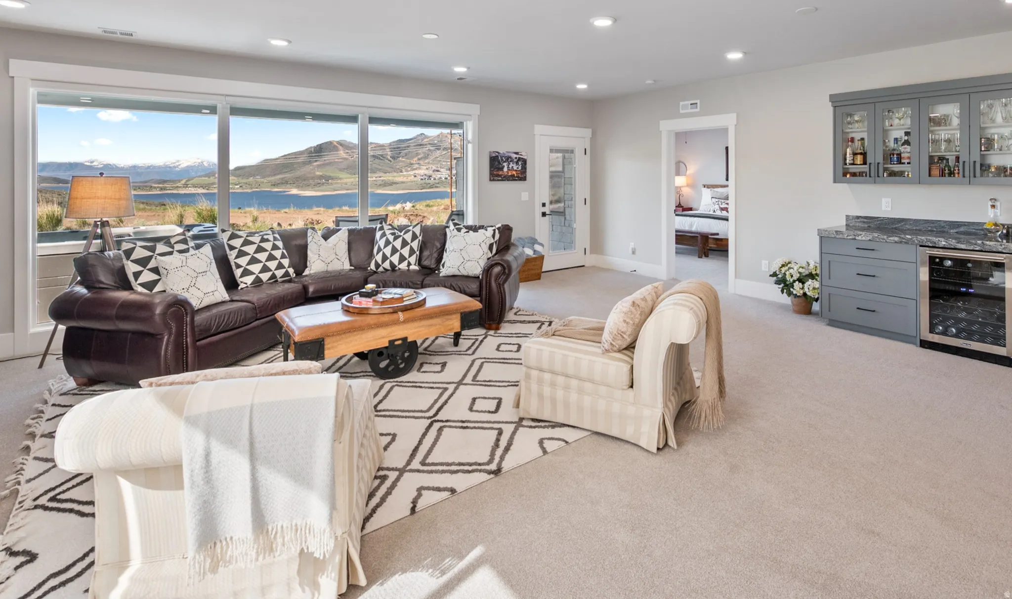 Spacious living area featuring expansive windows, recessed lighting, and a built-in wet bar with glass-front cabinetry, stone countertop, and beverage refrigerator