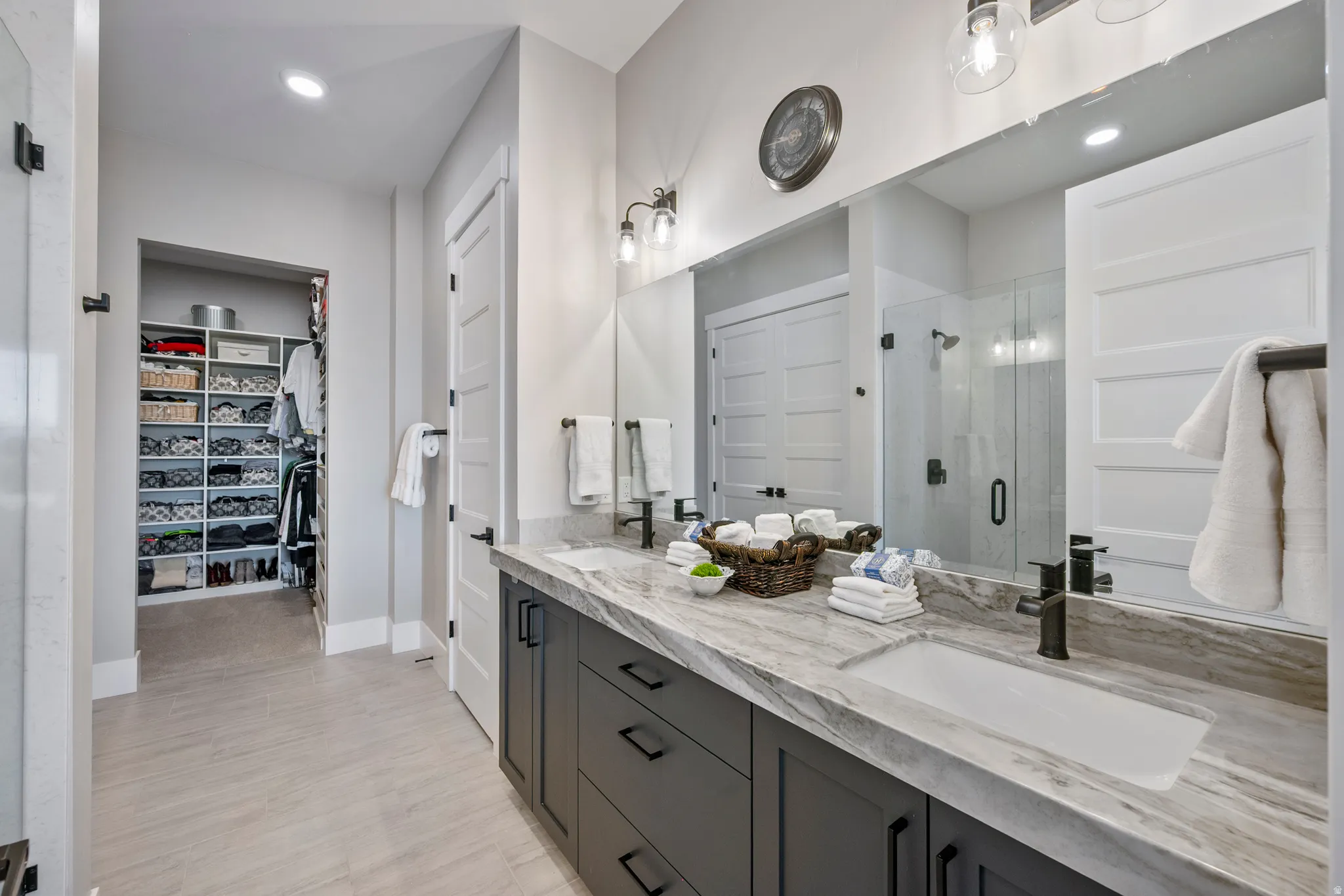 Spacious bathroom featuring a dual vanity with integrated sinks, a glass-enclosed shower, a large mirror, and recessed lighting