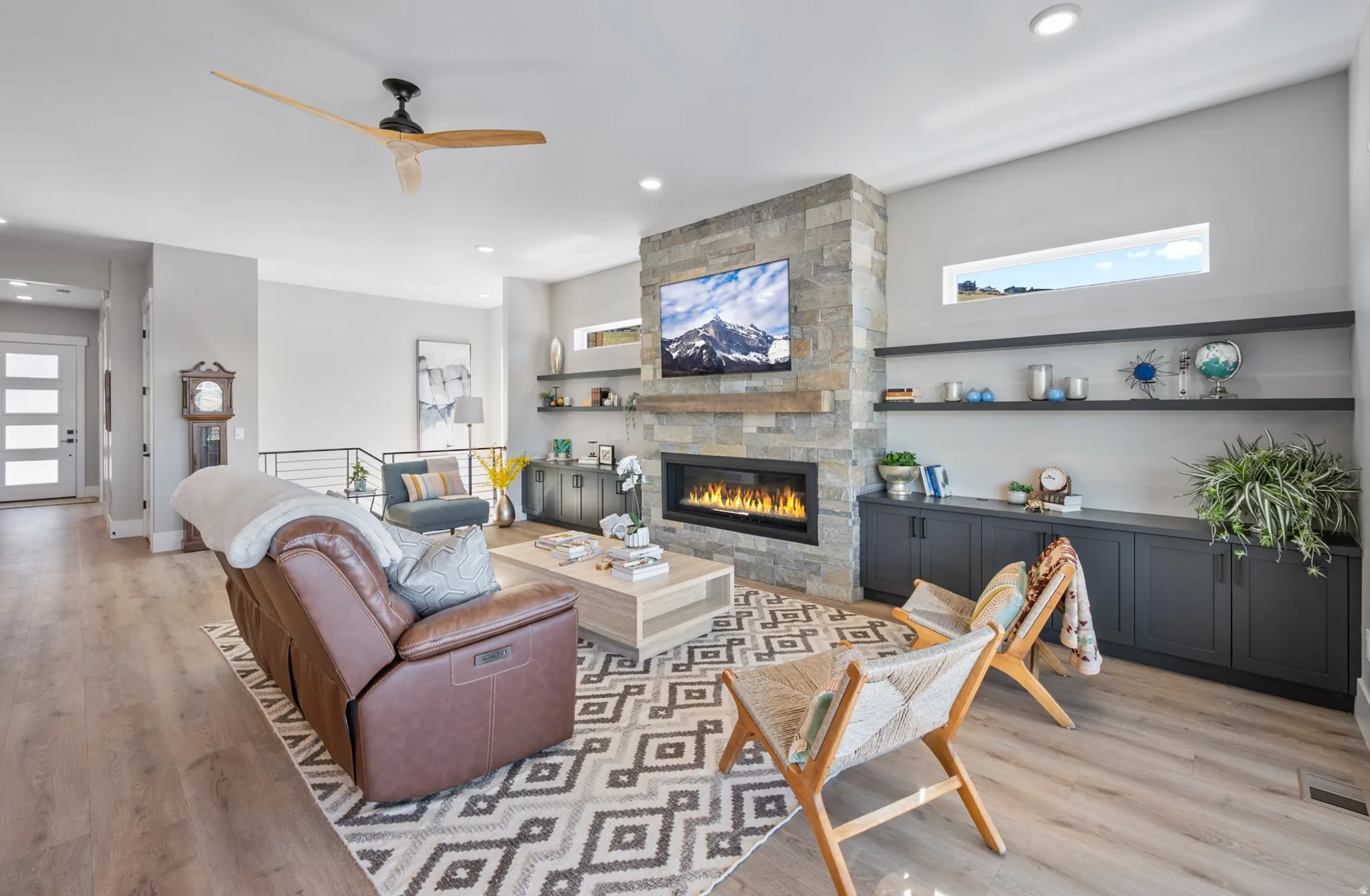 Open-concept living area featuring a stone-clad fireplace with an elongated linear insert, integrated wood mantle, and built-in shelving