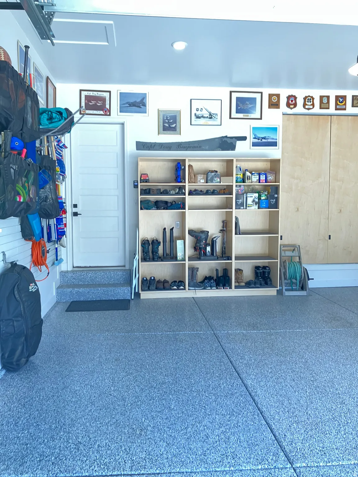 Garage featuring a speckled epoxy floor, built-in shelving, and light wood-finish storage cabinets