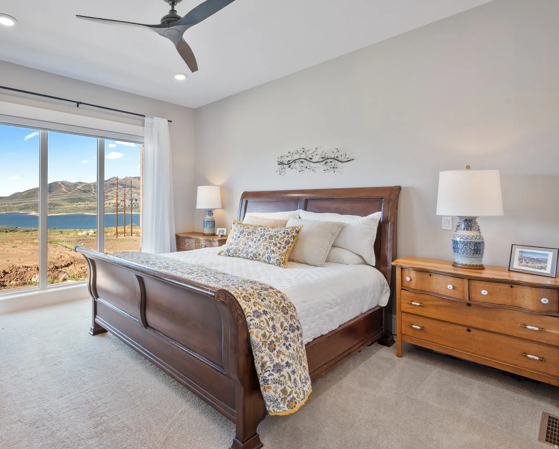 Full-height windows showcase a panoramic lake and mountain backdrop