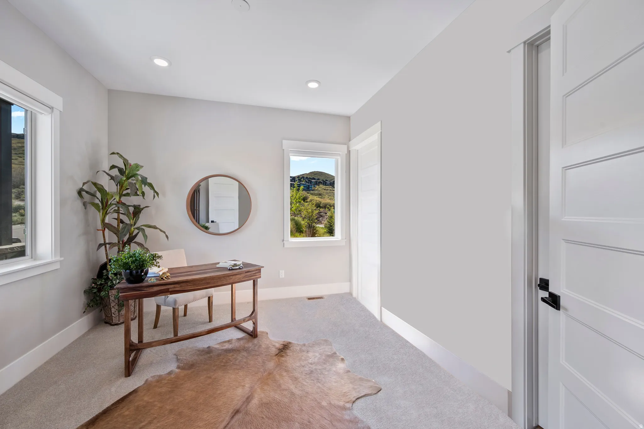 Light gray painted room with two windows, recessed lighting, and light-colored carpeting