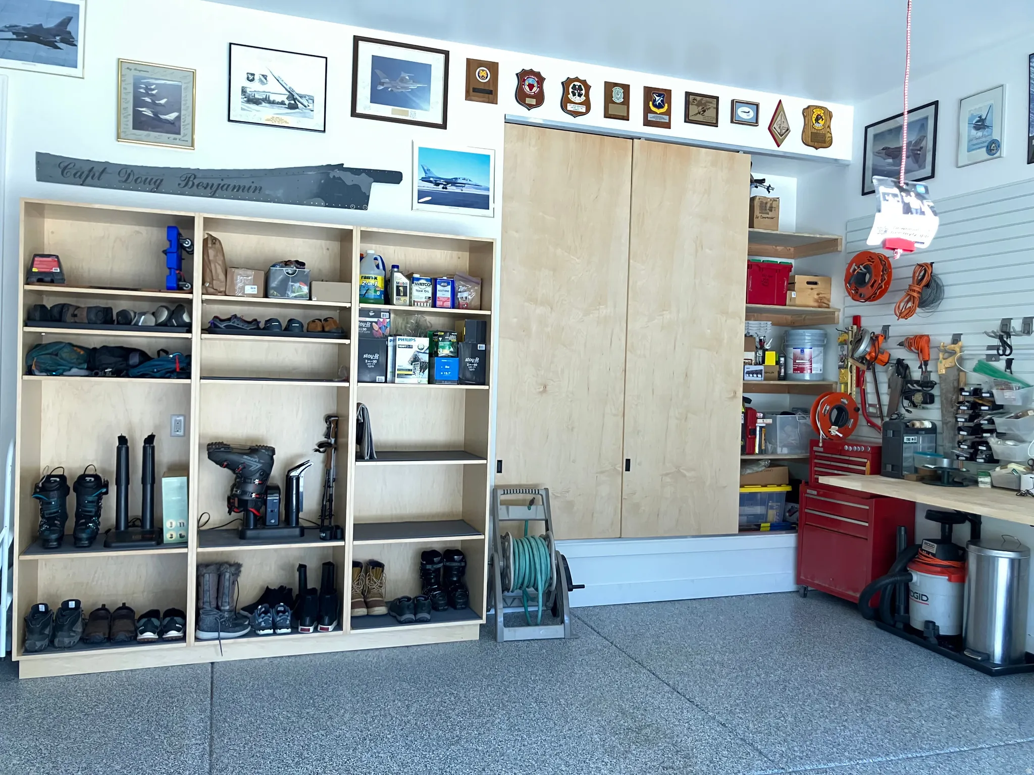 Garage with built-in light wood cabinetry, shelving, and wall-mounted storage organization