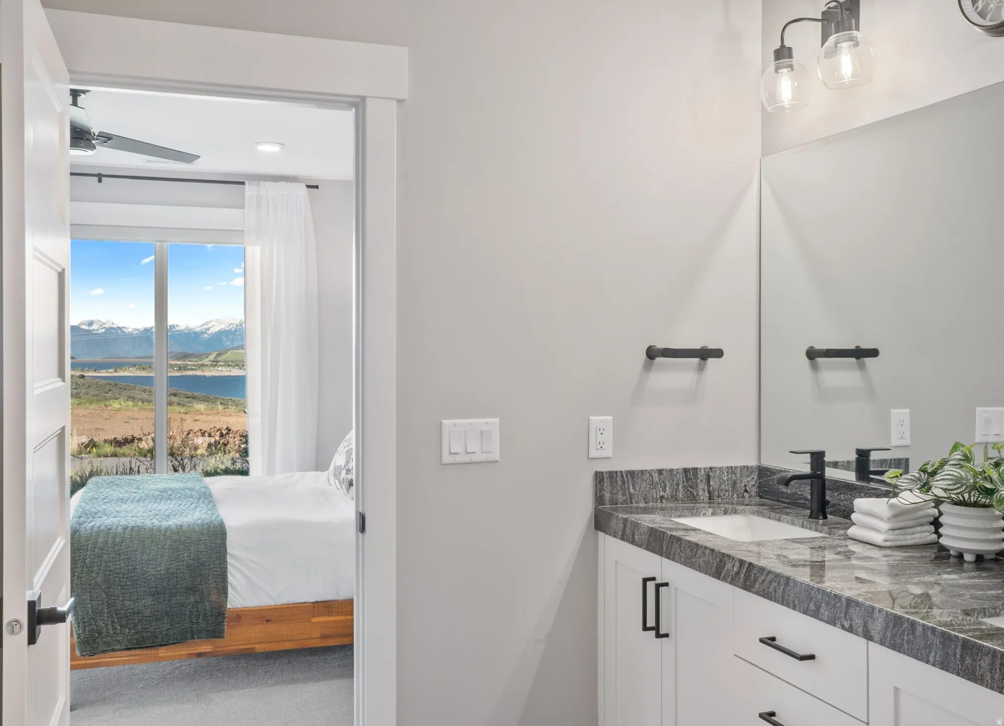Ensuite Bathroom vanity featuring a single undermount sink, dark-toned countertop, and white cabinetry with matte black hardware