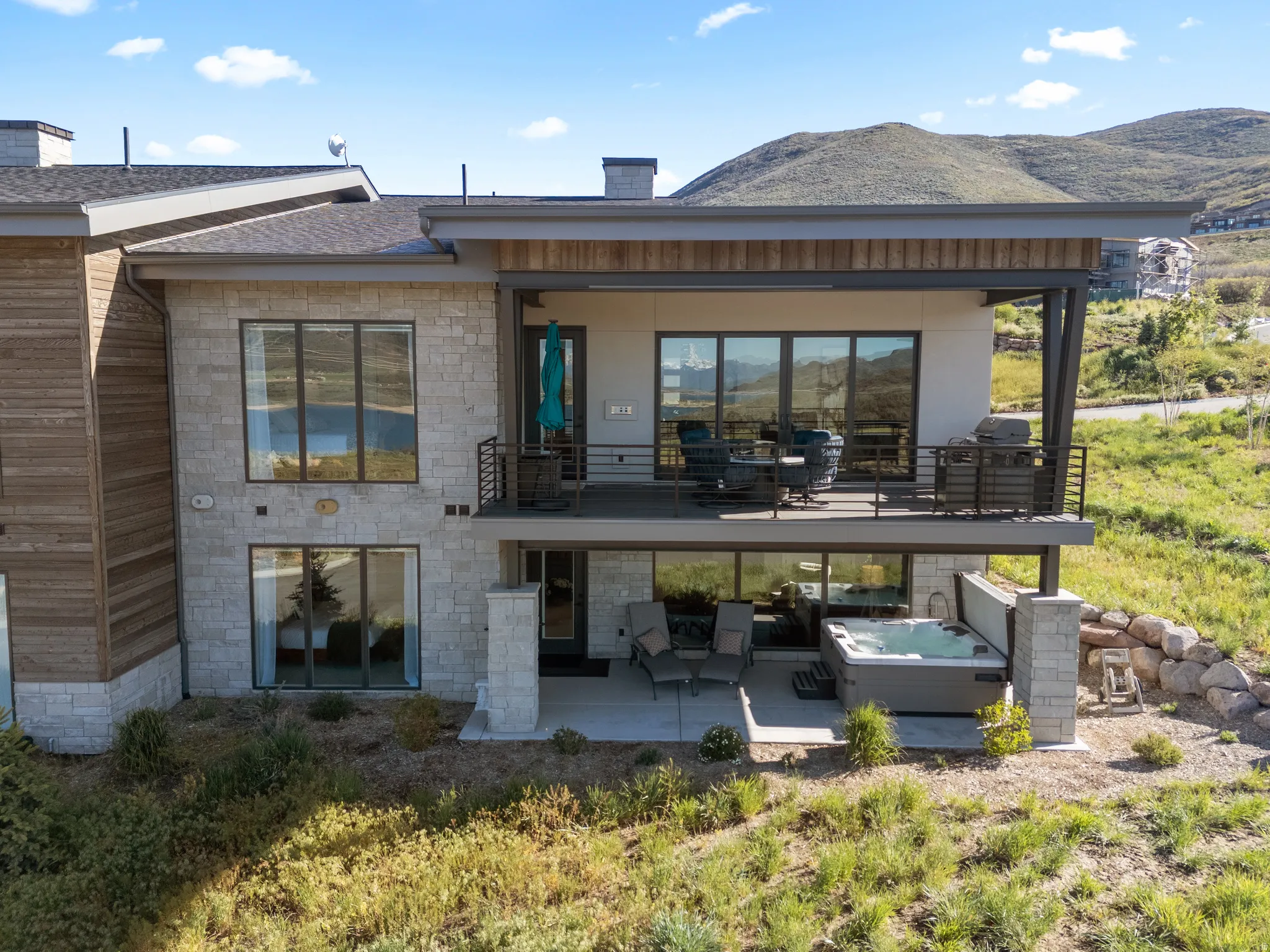 Modern exterior featuring stone facade, wood siding, and multiple outdoor living spaces