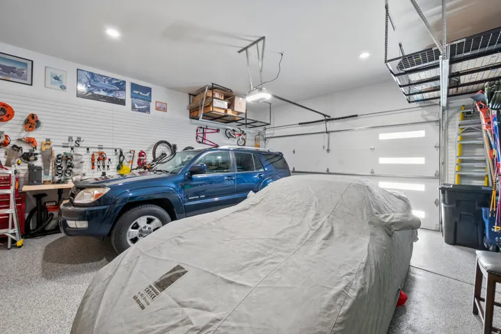 Spacious garage featuring an epoxy-coated floor, slatwall storage system, recessed lighting, and two sectional garage doors with frosted window inserts