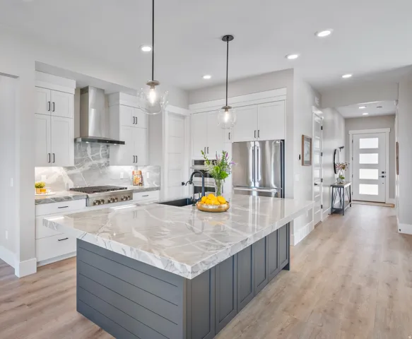 Kitchen featuring a large island with a marbled countertop, white cabinetry, integrated stainless steel appliances, and wood-finish flooring