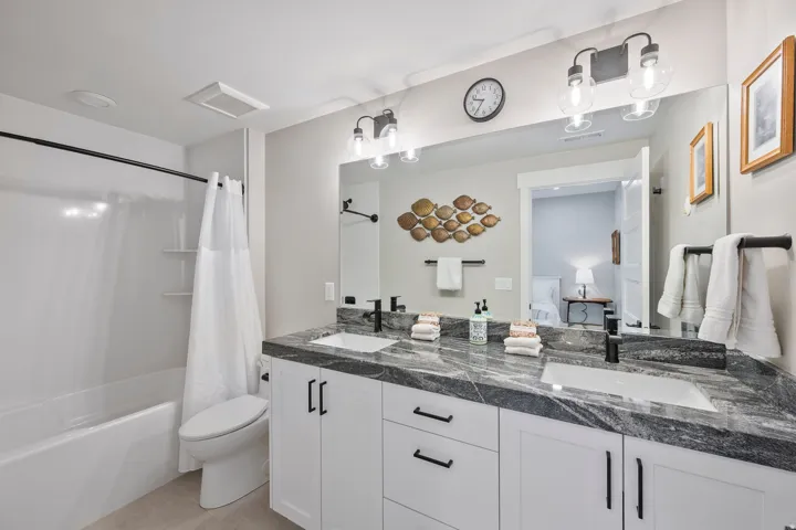 Ensuite Bathroom featuring a dual vanity with a patterned countertop, individual undermount sinks, and matte black hardware