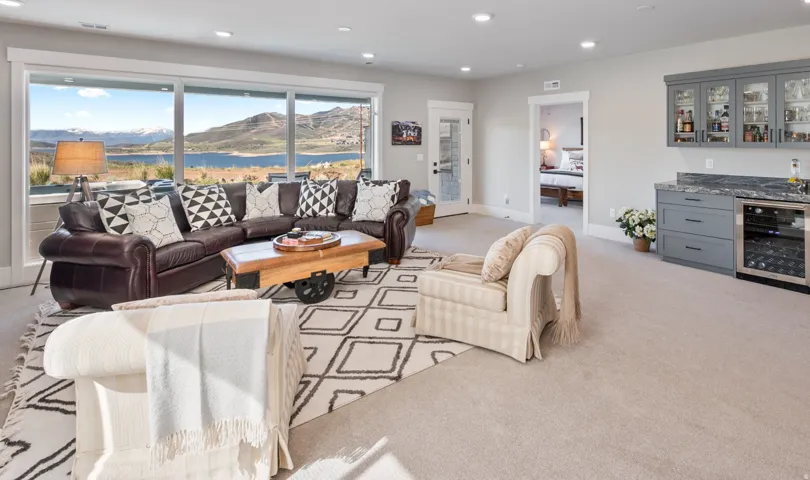 Spacious living area featuring expansive windows, recessed lighting, and a built-in wet bar with glass-front cabinetry, stone countertop, and beverage refrigerator