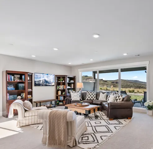 Spacious living area featuring expansive windows, recessed lighting, wall-to-wall carpeting, and built-in shelving units